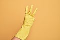 Hand of caucasian young man with cleaning glove over isolated yellow background counting number 3 showing three fingers Royalty Free Stock Photo