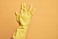 Hand of caucasian young man with cleaning glove over isolated yellow background greeting doing Vulcan salute, showing back of the