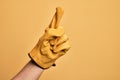 Hand of caucasian young man with gardener glove over isolated yellow background counting number one using index finger, showing Royalty Free Stock Photo