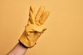 Hand of caucasian young man with gardener glove over isolated yellow background counting number 3 showing three fingers Royalty Free Stock Photo