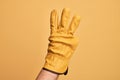 Hand of caucasian young man with gardener glove over isolated yellow background counting number 3 showing three fingers Royalty Free Stock Photo