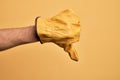 Hand of caucasian young man with gardener glove over isolated yellow background doing thumbs down rejection gesture, disapproval Royalty Free Stock Photo