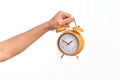 Hand of caucasian young man holding yellow vintage alarm clock over isolated white background Royalty Free Stock Photo