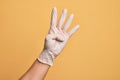 Hand of caucasian young man with medical glove over isolated yellow background counting number 4 showing four fingers Royalty Free Stock Photo