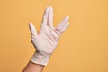 Hand of caucasian young man with medical glove over isolated yellow background greeting doing Vulcan salute, showing hand palm and
