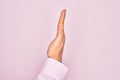 Hand of caucasian young man showing fingers over isolated pink background showing the side of stretched hand, pushing and doing Royalty Free Stock Photo