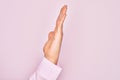 Hand of caucasian young man showing fingers over isolated pink background showing side of stretched hand, pushing and doing stop Royalty Free Stock Photo