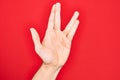 Hand of caucasian young man showing fingers over isolated red background greeting doing Vulcan salute, showing hand palm and Royalty Free Stock Photo