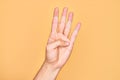 Hand of caucasian young man showing fingers over isolated yellow background counting number 4 showing four fingers Royalty Free Stock Photo