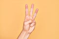 Hand of caucasian young man showing fingers over isolated yellow background counting number 3 showing three fingers Royalty Free Stock Photo