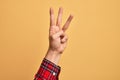 Hand of caucasian young man showing fingers over isolated yellow background counting number 3 showing three fingers Royalty Free Stock Photo