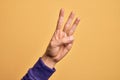 Hand of caucasian young man showing fingers over isolated yellow background counting number 3 showing three fingers Royalty Free Stock Photo