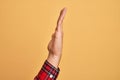 Hand of caucasian young man showing fingers over isolated yellow background showing side of stretched hand, pushing and doing stop Royalty Free Stock Photo