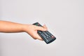 Hand of caucasian young woman changing television channel holding tv remote control over isolated white background Royalty Free Stock Photo