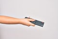 Hand of caucasian young woman changing television channel holding tv remote control over isolated white background Royalty Free Stock Photo