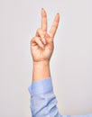 Hand of caucasian young woman doing victory symbol showing number two with streched fingers raised up over isolated white Royalty Free Stock Photo