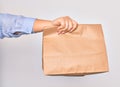Hand of caucasian young woman holding deliver paper bag of takeaway food over isolated white background Royalty Free Stock Photo