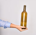 Hand of caucasian young woman holding empty glass botlle of wine over isolated white background Royalty Free Stock Photo