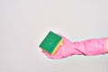 Hand of caucasian young woman wearing cleaning glove holding scourer sponge over isolated white background