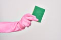 Hand of caucasian young woman wearing cleaning glove holding scourer sponge over isolated white background