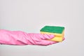 Hand of caucasian young woman wearing cleaning glove holding scourer sponge over isolated white background