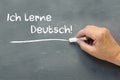 Hand on a chalkboard with the German words Ich lerne Deutsch (I
