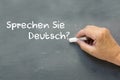 Hand on a chalkboard with the German words Sprechen Sie deutsch Royalty Free Stock Photo