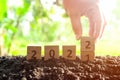 Hand changing year 2021 to 2022 in wooden blocks cubes with growing plant at sunrise. New year 2022, hope concept. Royalty Free Stock Photo