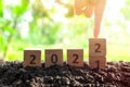 Hand changing year 2021 to 2022 in wooden blocks cubes with growing plant at sunrise. New year 2022, hope concept. Royalty Free Stock Photo