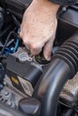 Hand checking the oil cap of a car engine