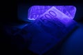 A hand checks a five hundred euro paper note in infrared light on a detector. Check for fake or genuine. Counterfeiting banknotes Royalty Free Stock Photo