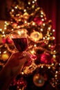 Hand cheering with tilted red wine glass against out of focus christmas tree lights, xmas festive celebration concept Royalty Free Stock Photo