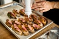 hand of chef add sauce on slices of baguette with meat and vegetable on tray Royalty Free Stock Photo