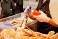 Hand of chef burning King crab legs and giant prawns on stove