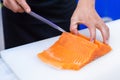 Hand of chef use knife preparing a fresh salmon on a cutting board, Japanese chef in restaurant slicing raw salmon, ingredient for Royalty Free Stock Photo