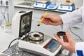 the hand of a chemical laboratory worker sprinkles earth with a yellow spoon into the equipment