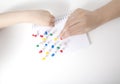 The hand of a child and a doctor sets multi-colored pins in a leaf on a white background. Autism development concept of