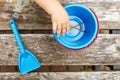 The hand of the child puts the toys in a plastic blue bucket, next is a scoop for sand. Close-up, no face Royalty Free Stock Photo