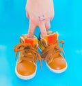 Baby shoes on a blue background with a hand Royalty Free Stock Photo