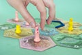 hand with chip under the playing field. game cards and chips on table close up. Takenoko Board game and leisure concept