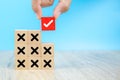 Hand choose check mark on cube wooden toy block with cross symbol for true or false changing mindset or way of adapting to change Royalty Free Stock Photo