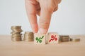 Hand choose increasing percent sign on wooden cube block with blurred stack of coins for business and finance , Royalty Free Stock Photo