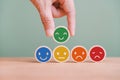 Hand choosing green happy smile face emoticon on circle wood, feedback rating and positive customer review, satisfaction survey Royalty Free Stock Photo