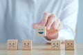 Hand choosing happy face among unhappy faces on wooden blocks. Positive thinking. Royalty Free Stock Photo