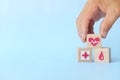 Hand choosing healthcare heartbeat icon on wooden blocks with copy space. Health top priority and medical insurance concept.