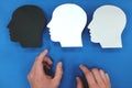 Hand choosing between multiple versions of self. Male silhouette head profile in blue background.