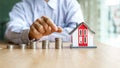 Hand choosing row of coin money house Planning to buy property or new home