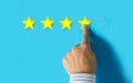 Hand choosing 4 yellow stars on blue background - Good feedback concept Royalty Free Stock Photo