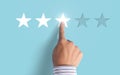 Hand choosing 3 stars rating on blue background - Average feedback concept Royalty Free Stock Photo