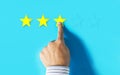 Hand choosing three stars rating on blue background Royalty Free Stock Photo